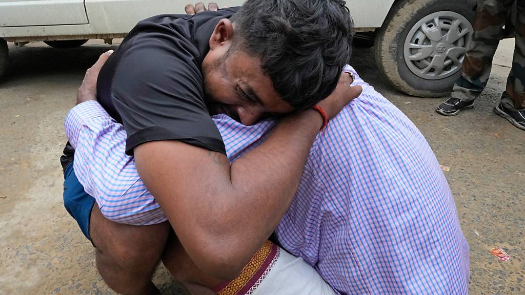 Ein Mann weint und umarmt den Schwiegervater seiner 37-jährigen Schwester Ruby, die Opfer einer Massenpanik in Indien wurde. Foto: Rajesh Kumar Singh/AP/dpa