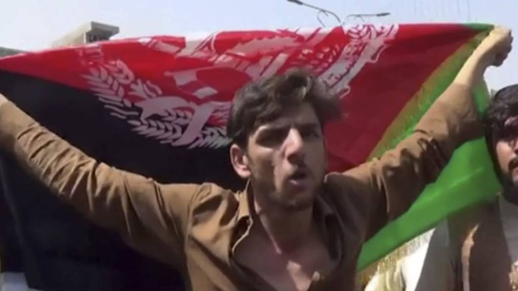 Ein Mann hält die Flagge Afghanistans während einer Demonstration in Jalalabad. Laut Videos in sozialen Medien finden in Afghanistan offenbar trotz des Siegeszugs der militant-islamischen Taliban weiter Demonstrationen mit der Nationalflagge statt. Foto: Uncredited/AP/dpa