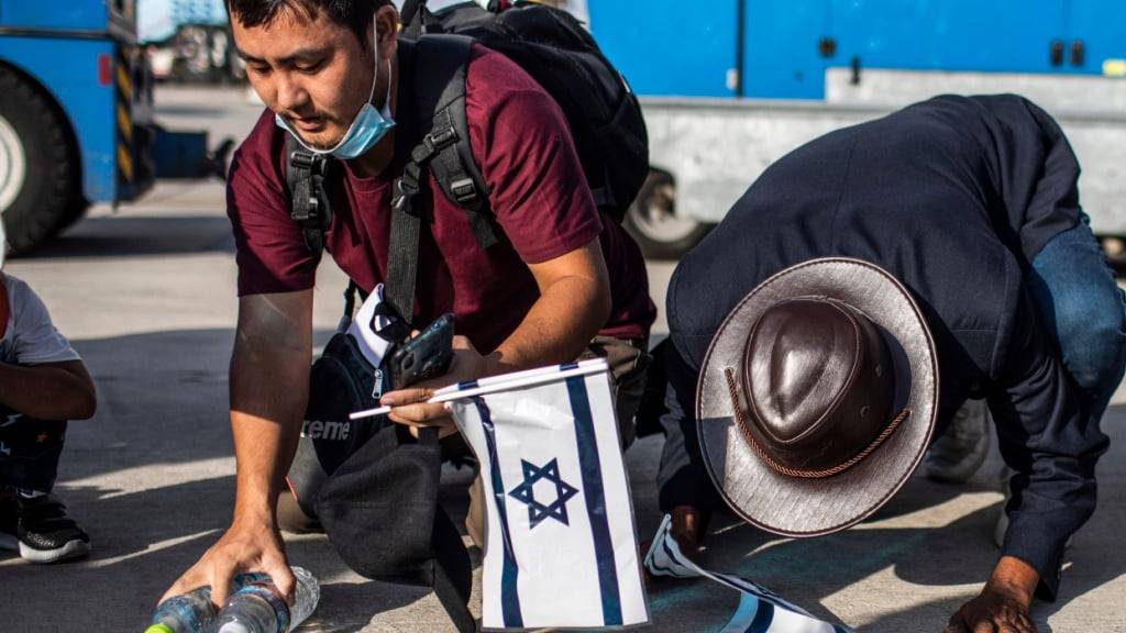 ARCHIV - Indische Immigranten der «Bnei Menashe» halten israelische Flaggen und knien bei ihrer Ankunft am Flughafen Ben Gurion auf dem Boden. Foto: Ilia Yefimovich/dpa