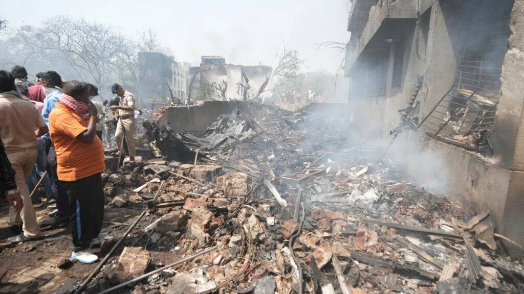 Menschen stehen um die Trümmer eines abgestürzten Flugzeugs in der nordwestindischen Stadt Ahmedabad im Bundesstaat Gujarat. Foto: Ajit Solanki/AP/dpa
