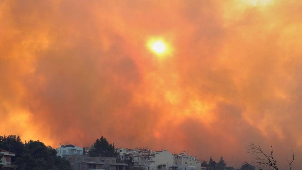 Rauch bedeckt den Himmel während eines Waldbrandes im nordwestlichen Vorort Kryoneri. Foto: Yorgos Karahalis/AP/dpa