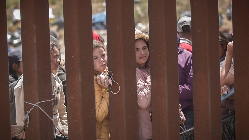 ARCHIV - Frauen stehen hinter der Grenzmauer zwischen Mexiko und USA und hoffen darauf, in die USA einreisen zu können. Foto: Antonio Castaneda/dpa