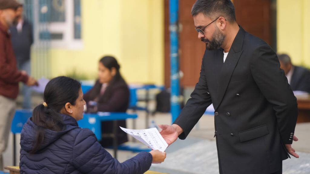 Balendra Shah (r), ehemaliger Bürgermeister der Stadt Kathmandu und Premierministerkandidat der Rastriya Swatantra Party, zeigt seinen Personalausweis, bevor er seine Stimme in einem Wahllokal für die Parlamentswahl abgibt. Foto: Niranjan Shrestha/AP/dpa