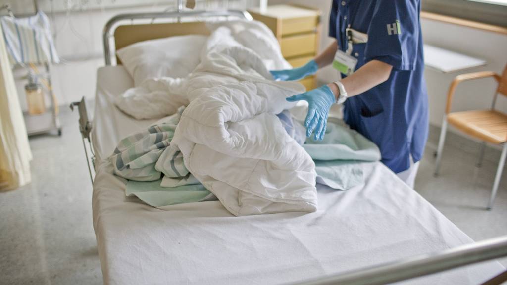 Eine Mitarbeiterin des Krankenhauses in Flawil im Kanton St. Gallen wechselt auf der Intensivstation die Bettwäsche eines Patienten.