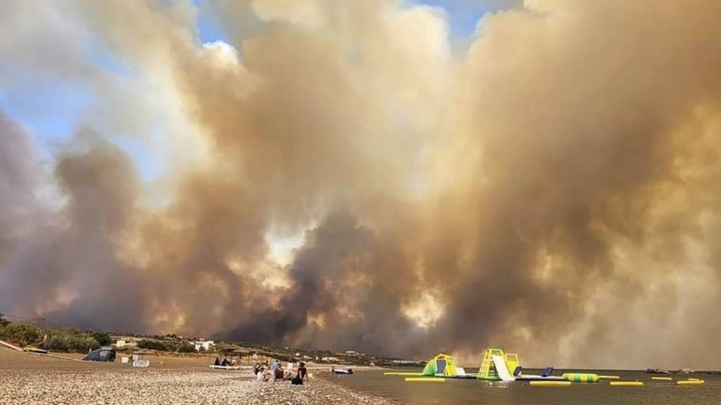 Dichte Rauchwolken eines Waldbrandes steigen auf der griechischen Insel Rhodos in den Himmel. Foto: uncredited/Rhodes.Rodos/AP/dpa