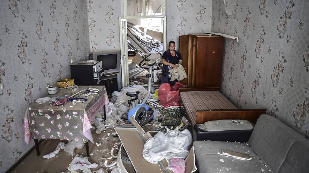 Eine Frau steht in ihrem beschädigten Haus, welches durch Beschuss durch armenische Soldaten beschädigt wurde. Foto: Ismail Coskun/AP/IHA/dpa