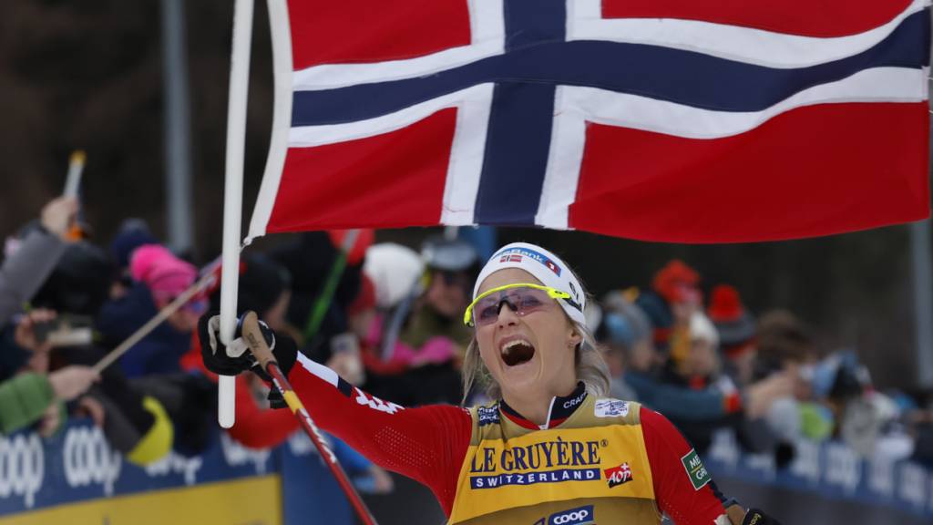 Therese Johaug läuft mit der norwegischen Flagge als Siegerin auf der Alpe Cermis ein