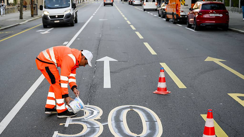 Ein Angestellter der Stadt Freiburg markiert im Oktober 2023 auf einer grösseren Freiburger Strasse Höchstgeschwindigkeit 30. (Archivbild)