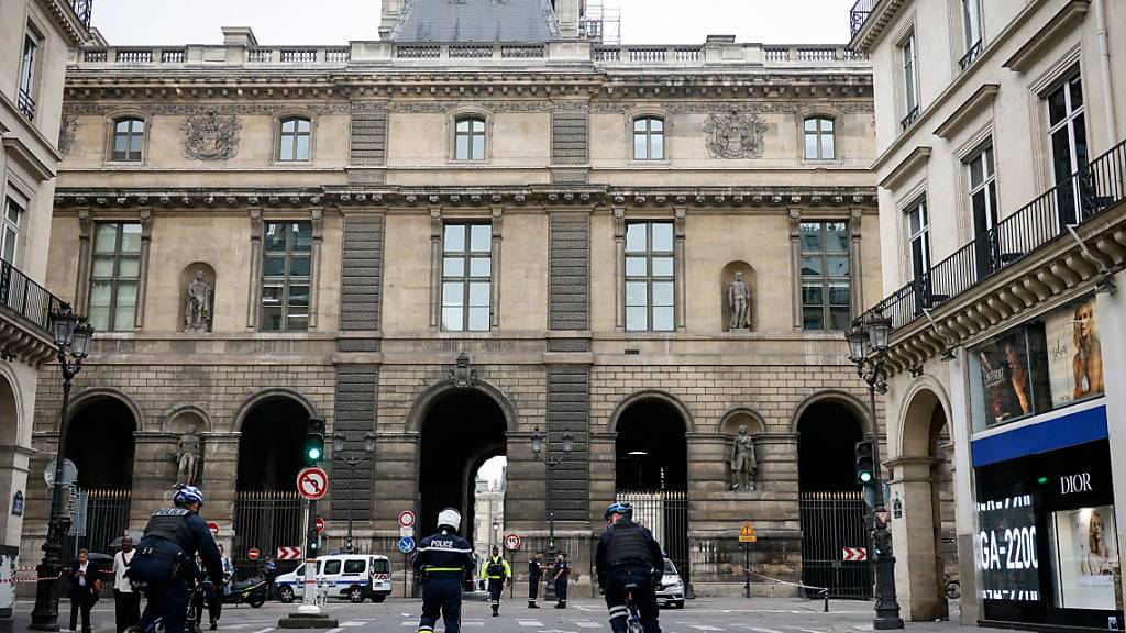 Polizeibeamte stehen vor dem Louvre in Paris Wache, der wegen einer Bombendrohung geräumt worden. Foto: Thomas Padilla/AP/dpa