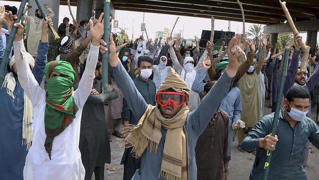 Anhänger von TLP-Parteiführer Rizvi halten während eines Protests Bambusstöcke und Steine in die Höhe. Foto: Muhammad Sajjad/AP/dpa