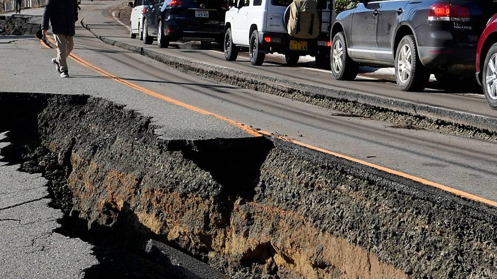 Autos stauen sich auf einer teilweise eingestürzten Straße, nach einem starken Erdbeben in der Nähe der Stadt Anamizu. Die Zahl der Todesopfer infolge einer Serie starker Erdbeben an der Westküste Japans ist weiter gestiegen. Foto: Hiro Komae/AP/dpa
