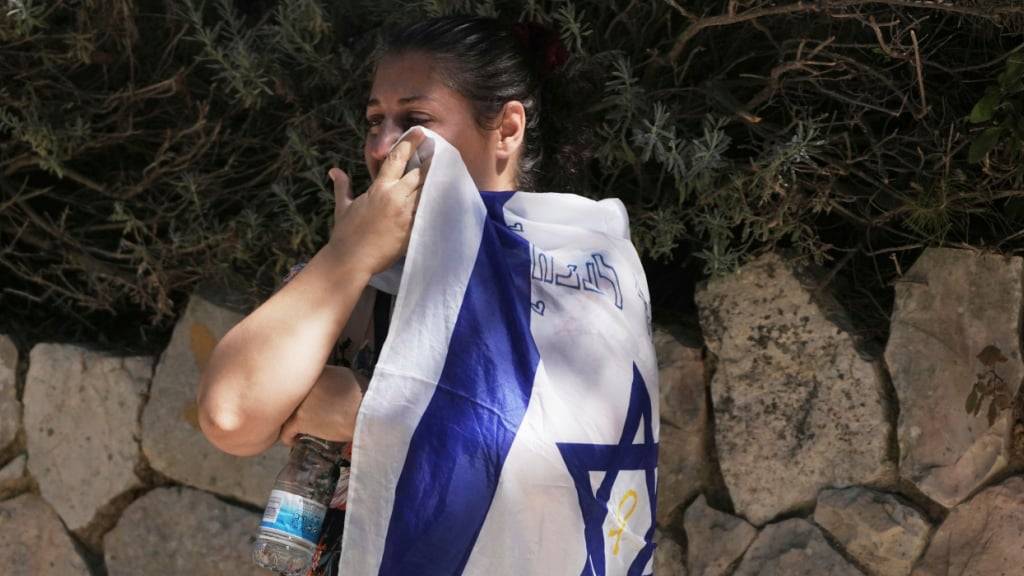 Eine Trauernde wischt ihre Tränen mit der israelischen Nationalflagge bei der Beerdigung von Noam Aharon Musgadian, Stabsfeldwebel der israelischen Streitkräfte, der im Gazastreifen gefallen ist, auf dem Militärfriedhof Mount Herzl in Jerusalem. Foto: Maya Alleruzzo/AP/dpa