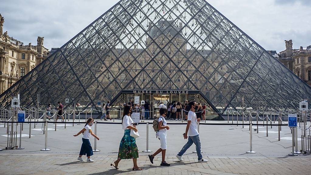 ARCHIV - Eine Familie mit Schutzmasken geht am Louvre vorbei. (zu dpa «Corona-Krise: Frankreich kommt seinen großen Museen zu Hilfe») Foto: Kamil Zihnioglu/AP/dpa