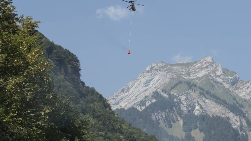 Ein Helikopter transportiert Löschwasser zum Absturzort am Lopper in Hergiswil NW. (Archivbild)