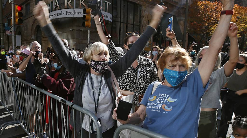 Menschen mit Mund-Nasen-Schutz feiern vor dem Pennsylvania Convention Center, nachdem der demokratische Präsidentschaftskandidat Joe Biden zum Sieger erklärt wurde. Foto: Rebecca Blackwell/AP/dpa