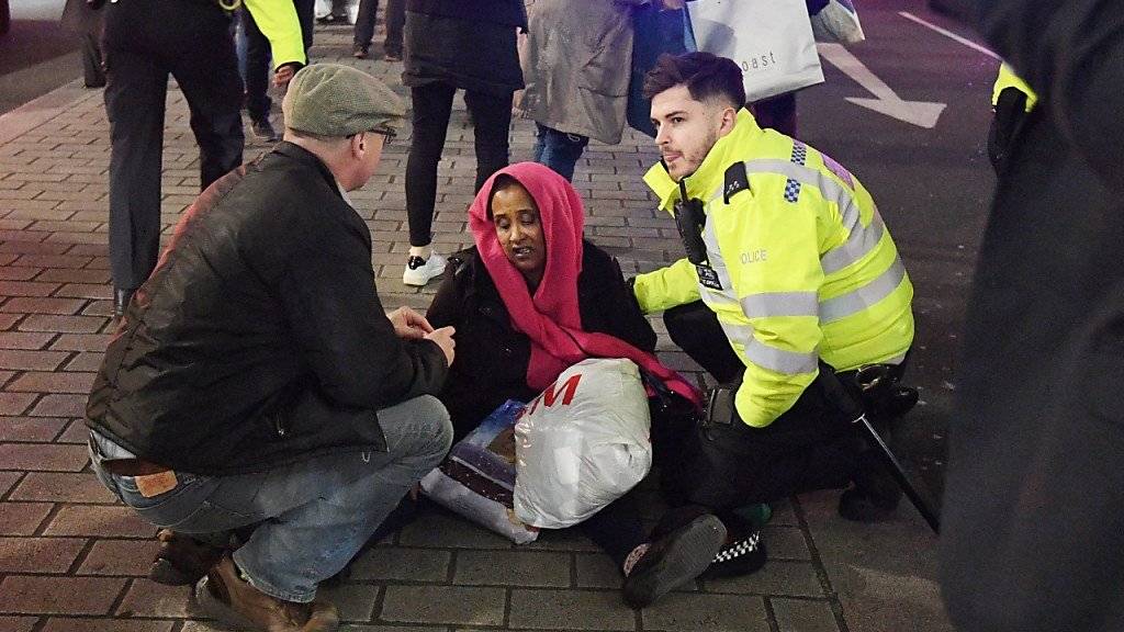 Polizisten helfen einer Frau nach der Massenpanik in London. Zwei Männer wurden deswegen befragt - aber nicht festgenommen.