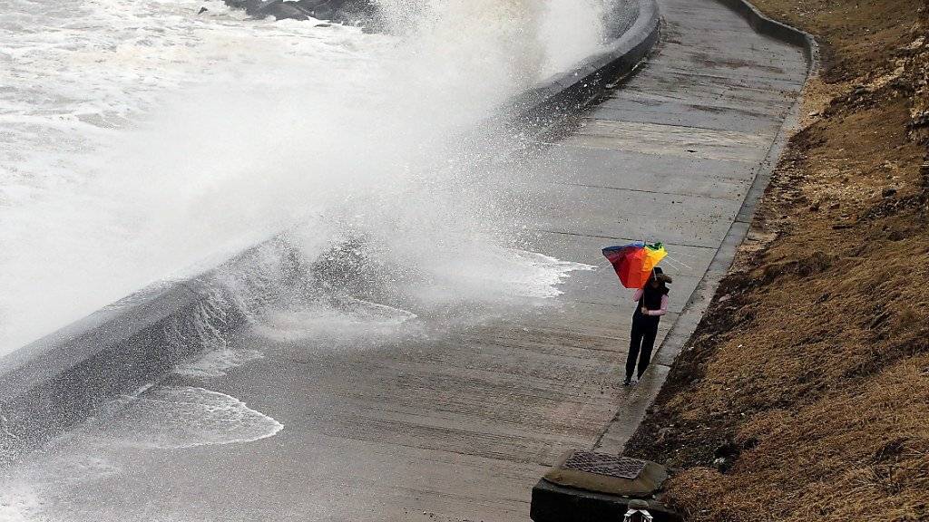 Eine Spaziergängerin kämpft mit ihrem Schirm an der Seepromenade von Seaham im Nordosten Englands.