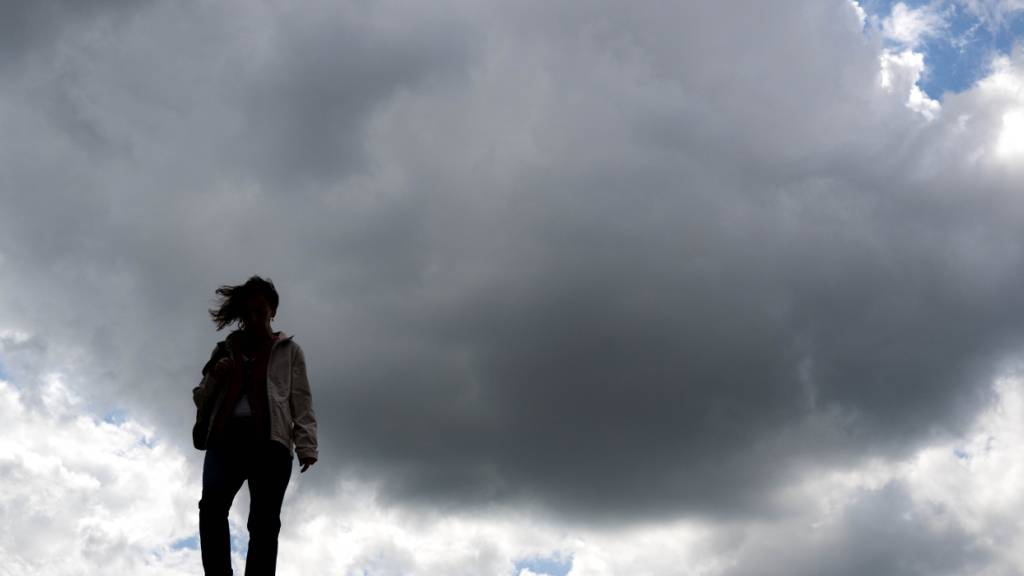 ARCHIV - Eine Frau läuft unter dunklen Wolken. Foto: Sina Schuldt/dpa