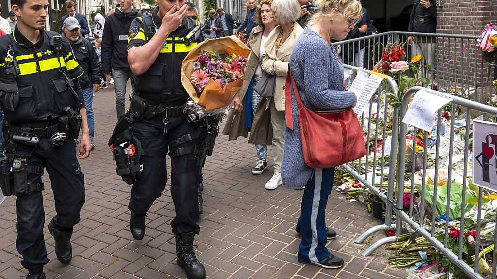 dpatopbilder - ARCHIV - Polizisten bringen einen Blumenstrauß zu dem Blumenmeer für den Reporter Peter R. de Vries. Bei der ersten öffentlichen Sitzung berief sich der mutmaßliche Mörder heute auf sein Schweigerecht. Foto: Evert Elzinga/ANP/dpa