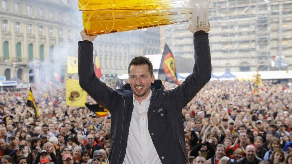 SCB-Trainer Lars Leuenberger hält den Meisterpokal hoch und lässt sich von der Menschenmenge auf dem Bundesplatz feiern.