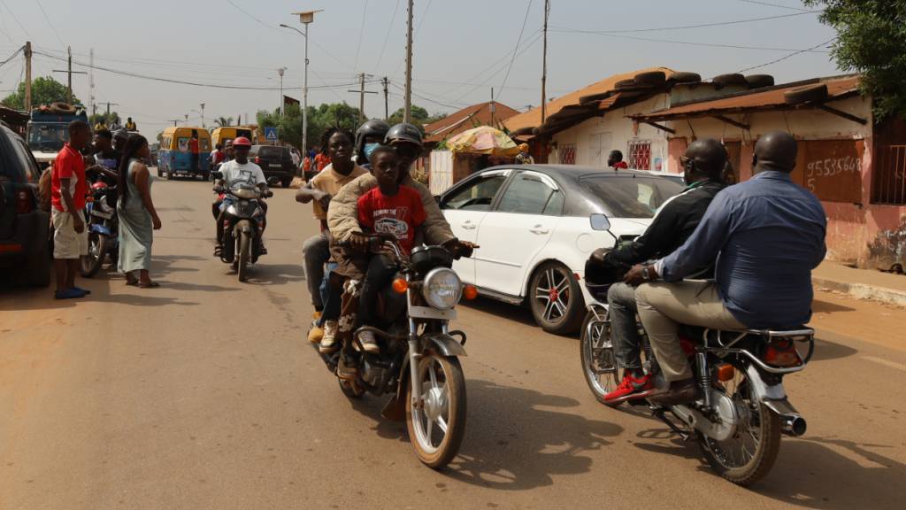 Menschen fahren auf Motorradtaxis auf der Straße.  Wenige Tage nach einer Wahl in Guinea-Bissau droht ein gewaltsamer Umsturz in dem westafrikanischen Küstenland. Foto: Darcicio Barbosa/AP/dpa