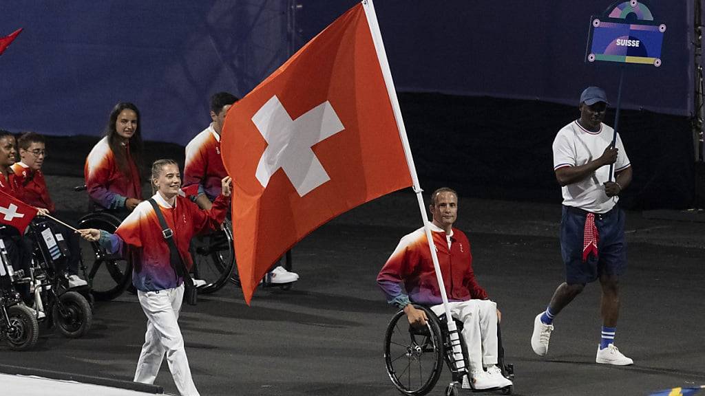 Elena Kratter und Marcel Hug tragen die Schweizer Flagge auf die Place de la Concorde