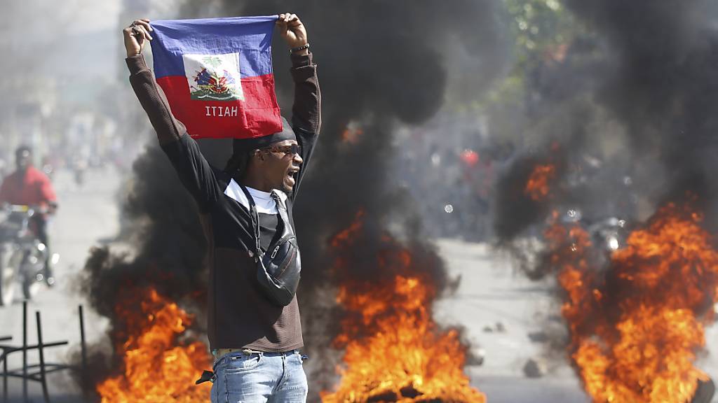 dpatopbilder - Ein Demonstrant hält eine haitianische Flagge während Protesten für den Rücktritt von Premierminister Henry hoch. Foto: Odelyn Joseph/AP