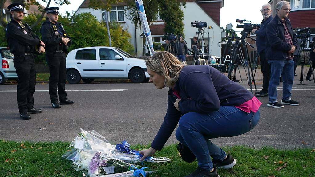 Eine Frau legt Blumen am Tatort in der Nähe der Belfairs Methodist Church nieder, wo der konservative Abgeordnete David Amess zum Opfer eines Messerangriffs wurde. In Großbritannien herrscht nach dem tödlichen Angriff Bestürzung. Von mehreren Seiten kamen bereits Beileidsbekundungen für Amess.