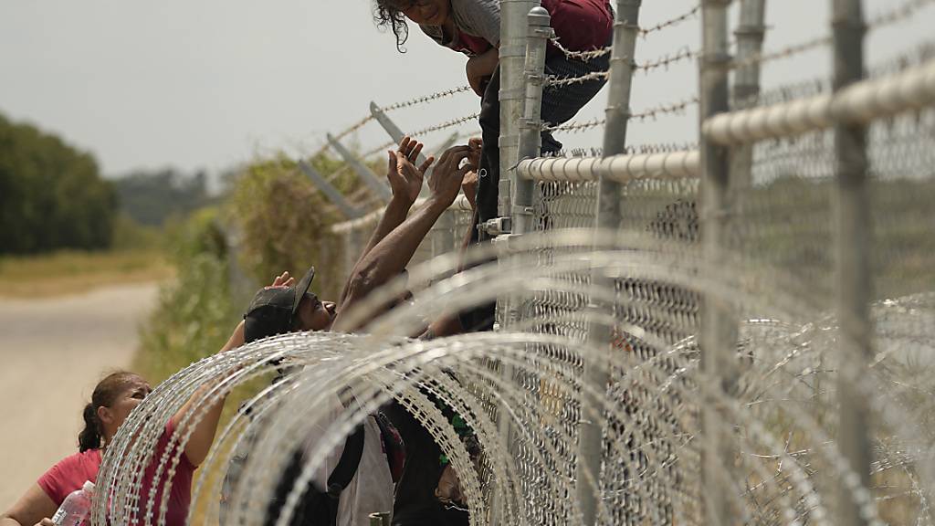dpatopbilder - Migranten, die den Rio Grande von Mexiko in die USA überquert haben, klettern in Texas über einen Zaun mit Stacheldraht. Foto: Eric Gay/AP