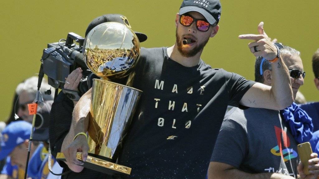 Stephen Curry lässt sich bei der NBA-Meisterparade der Golden State Warriors von den Fans mit der Larry O'Brien Trophy feiern