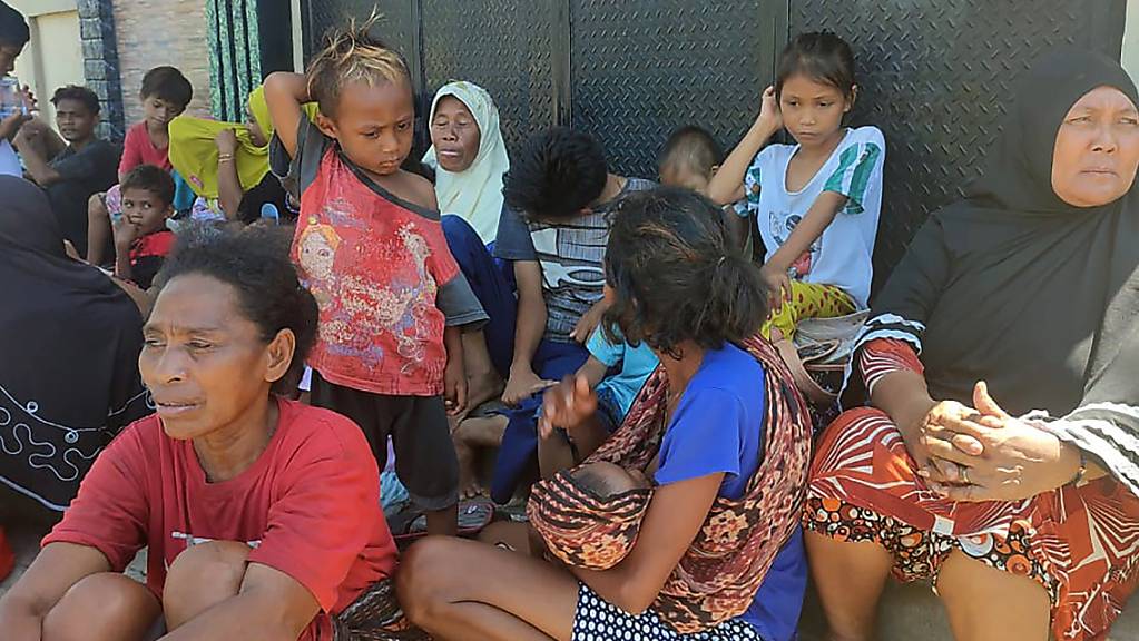 Menschen sitzen im indonesischen Maumere nach einem Erdbeben vor ihren Häusern. Foto: Str/AP/dpa
