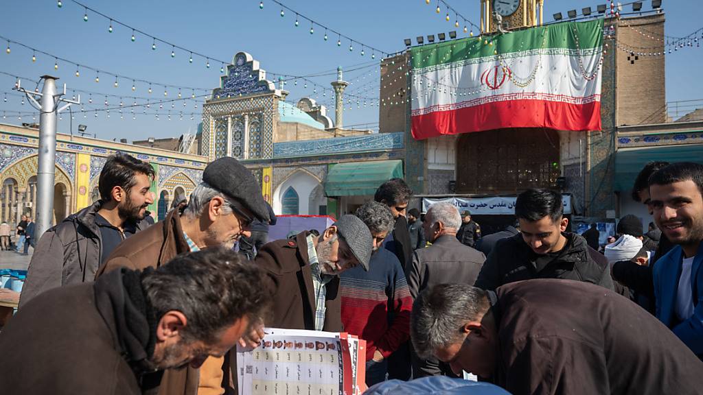 Eine Gruppe von Männern betrachtet die Listen von Kandidaten in Teheran in einem schiitischen Heiligtum im Süden der Hauptstadt. Foto: Arne Bänsch/dpa