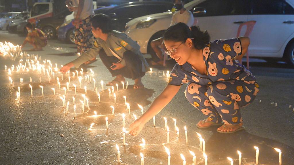 Demonstrantinnen zünden auf einer Straße Kerzen an. Trotz einer nächtlichen Ausgangssperre sind in Myanmar zahlreiche Menschen auf die Straße gegangen, um gegen die Militärjunta zu protestieren. Polizei und Militär gehen seit Wochen mit zunehmender Brutalität gegen die Bevölkerung vor. Foto: Uncredited/AP/dpa