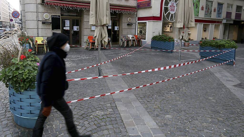 Ein Mann mit Mund-Nasen-Schutz geht an einem geschlossenen Cafe in der Wiener Innenstadt vorbei. Foto: Ronald Zak/AP/dpa