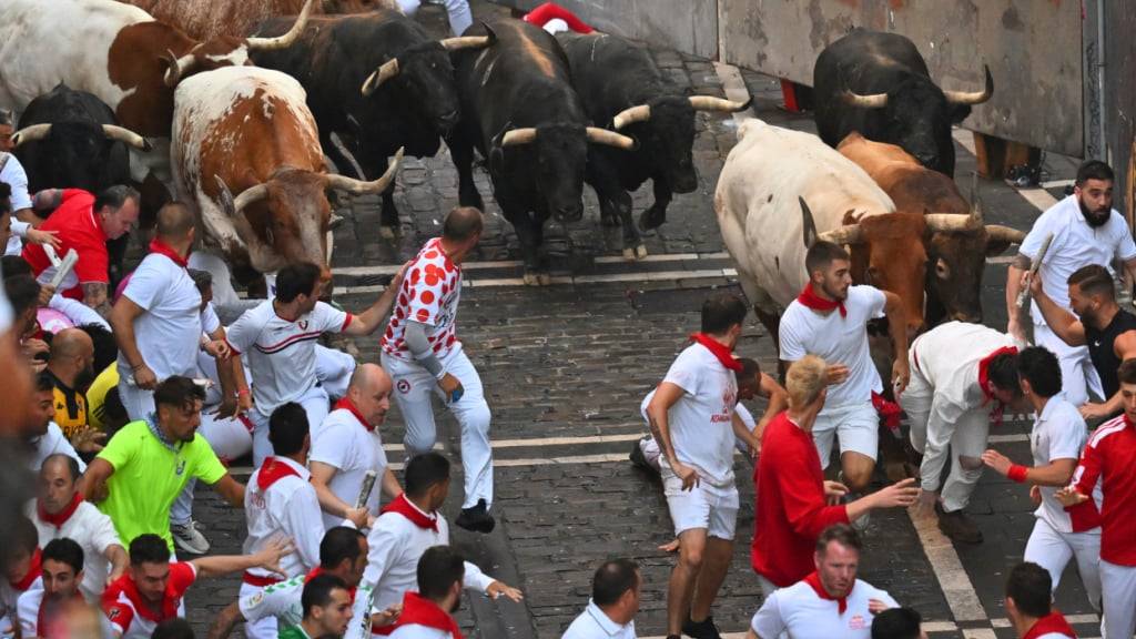 Teilnehmer treiben die Stiere von La Palmosilla am siebten Tag der San Fermin-Festlichkeiten durch die Innenstadt. Foto: Miguel Oses/AP/dpa