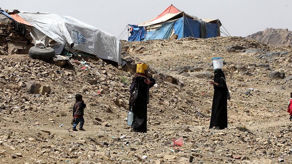 Frauen tragen Wasser in ihr behelfsmässiges Flüchtlingslager im Jemen.