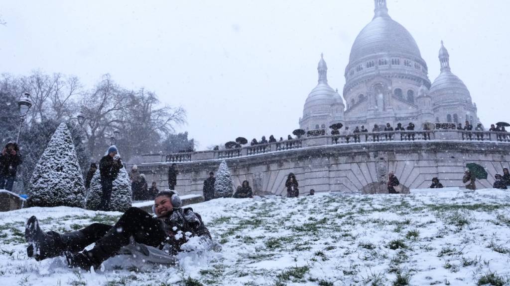 dpatopbilder - Menschen vergnügen sich im Schnee an einem Hang bei der Basilika Sacre-Coeur in Paris. Foto: Aurelien Morissard/AP/dpa