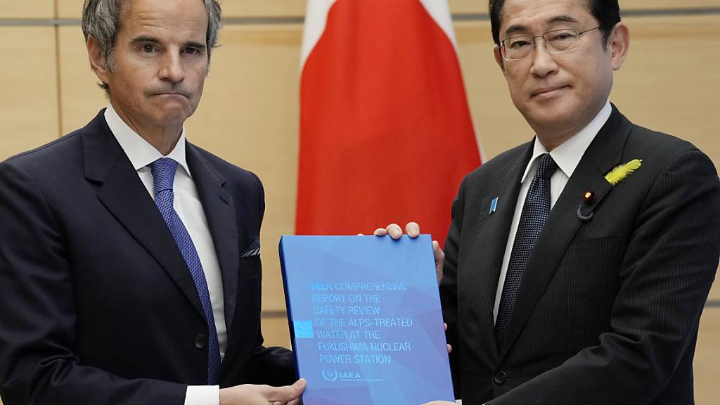 dpatopbilder - Der Generaldirektor der Internationalne Atomenergie-Organisation Rafael Mariano Grossi (l) überreicht Japans Premierminister Fumio Kishida einen Bericht über die Freisetzung von behandeltem Wasser aus Fukushima. Foto: Eugene Hoshiko/Pool AP/AP/dpa
