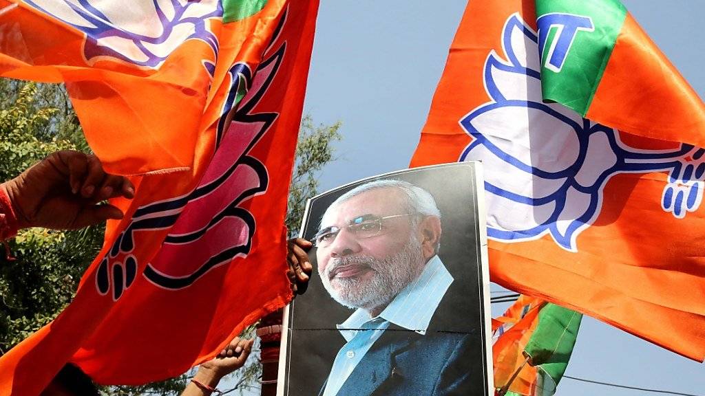 Anhänger von Indiens Regierungschef Narendra Modi feiern mit Fahnen und Modi-Bild ihren Wahlsieg in Uttar Pradesh