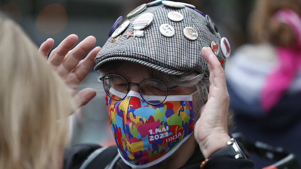 An einer Kundgebung zum Tag der Arbeit demonstriert ein Mann mit einer farbenprächtigen Corona-Gesichtsmaske der Gewerkschaft Unia  im Zentrum von Zürich.