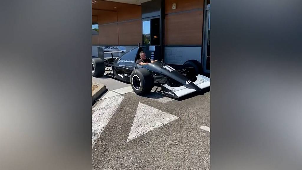 Mann fährt mit Formel-1-Auto durch McDonald's-Drive-In