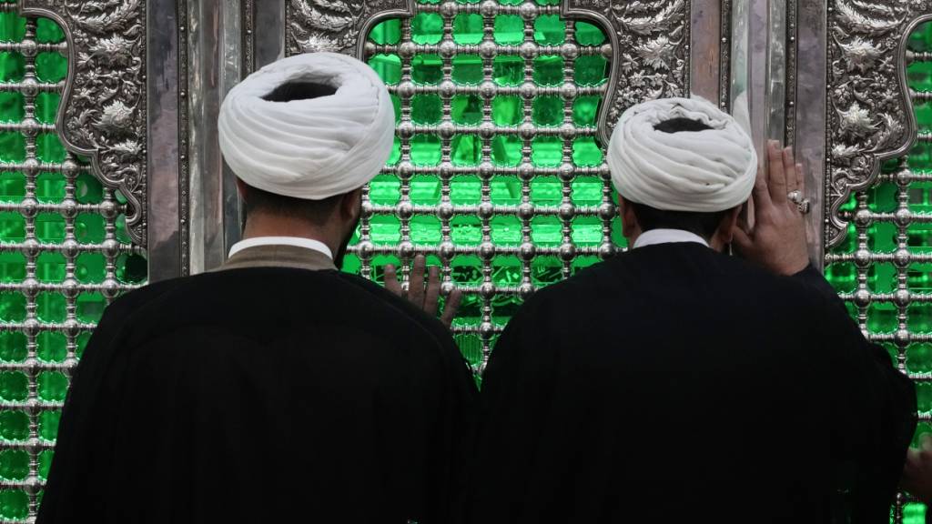 ARCHIV - Kleriker beten in Schahr-e-Rai, südlich von Teheran, während sie die Gitterstäbe des Grabes des schiitischen Heiligen Hamsah berühren. Foto: Vahid Salemi/AP/dpa/Symbolbild