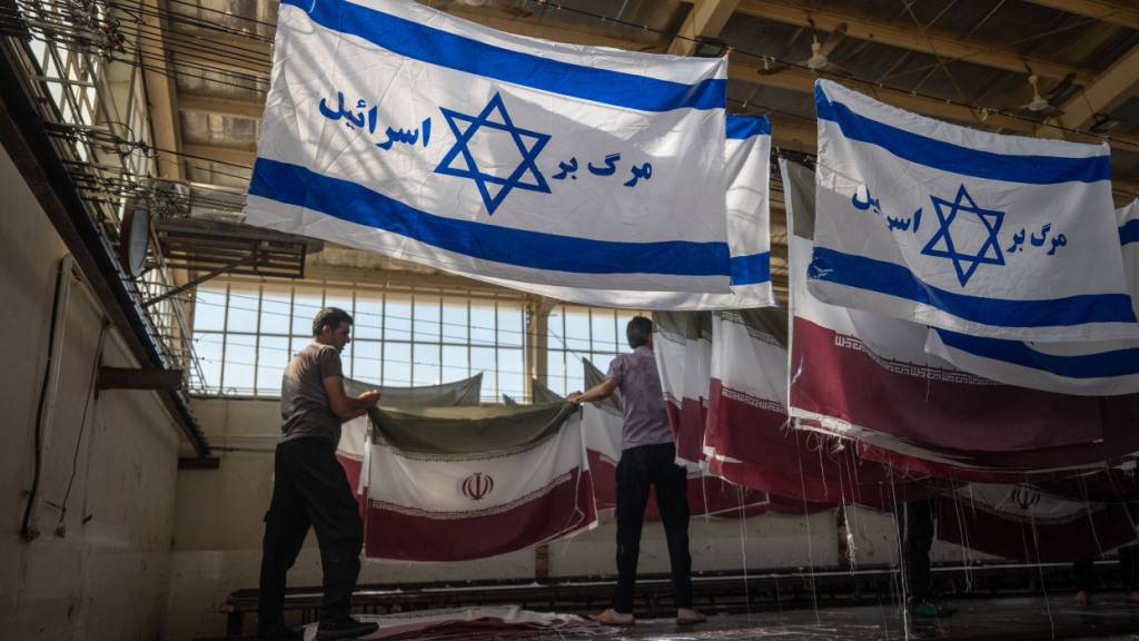 ARCHIV - Mitarbeiter einer Fabrik hängen Flaggen nach dem Trocknen ab. Amerikanische Flaggen im Iran sind eine Seltenheit. Foto: Arne Immanuel Bänsch/dpa