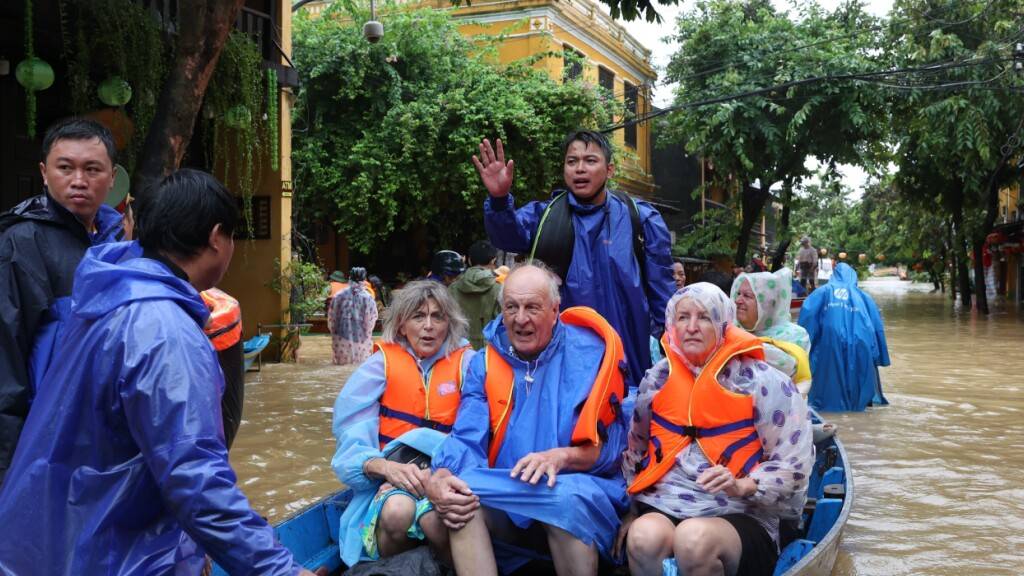 ARCHIV - Touristen werden mit einem Boot aus den Fluten evakuiert. Nach Rekordregenfällen in Vietnam stehen viele Straßen unter Wasser. Foto: Phan Anh Dung/VNA via AP/dpa