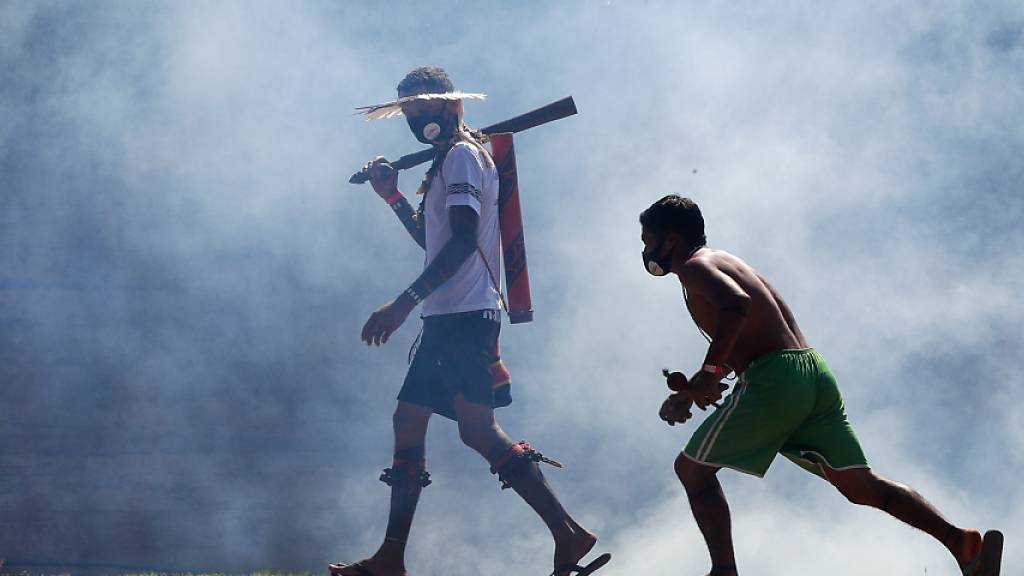 Indigene gehen durch Rauch von Tränengas, nachdem sie während eines Protestes vor dem Kongress mit der Polizei zusammengestoßen sind. Foto: Eraldo Peres/AP/dpa
