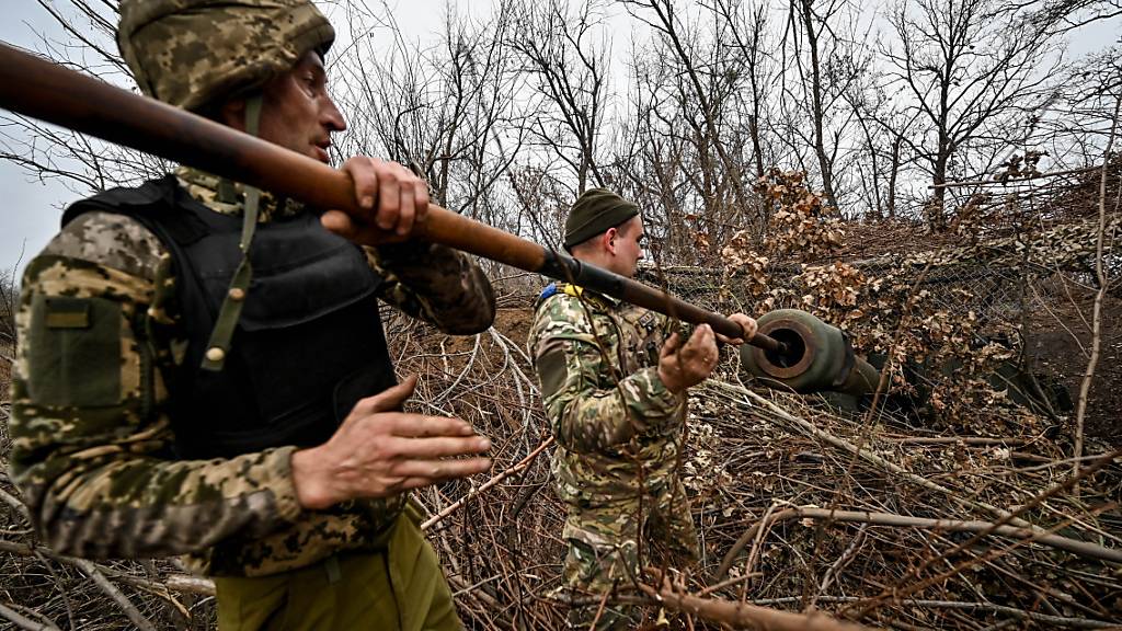 dpatopbilder - Zwei Soldaten reinigen das Rohr einer getarnten selbstfahrenden Panzerhaubitze. Foto: ---/Ukrinform/dpa