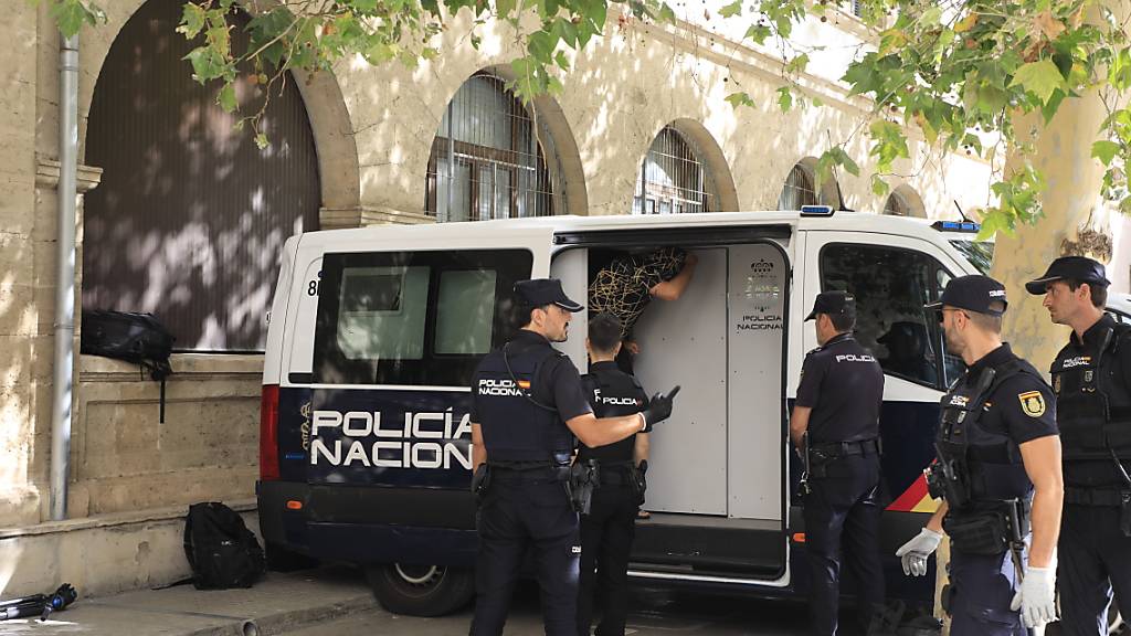 Polizisten stehen um den Transport, in dem die Verdächtigen zum Termin mit dem Haftrichter auf der Balearische Insel gebracht wurden. Foto: Clara Margais/dpa