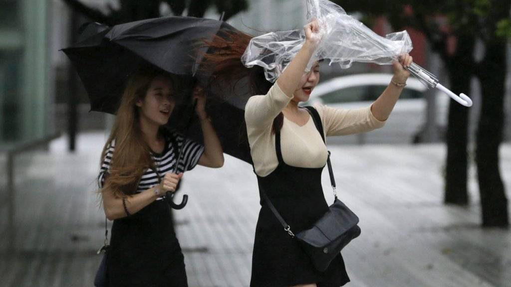 Der starke Wind zerzaust die Regenschirme dieser Japanerinnen.