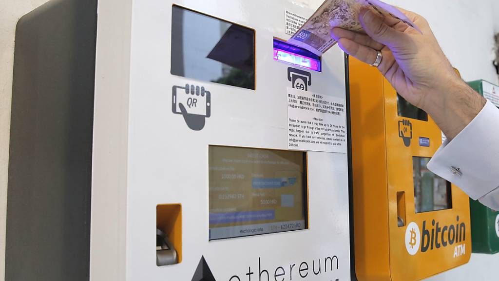 Die Kryptowährung Ether hat ein Kurshoch erreicht. Im Bild: Eine Person benutzt einen Ether-Geldautmoaten in Hongkong, der neben einem Bitcoin-Geldautomaten steht. (Symbolbild)