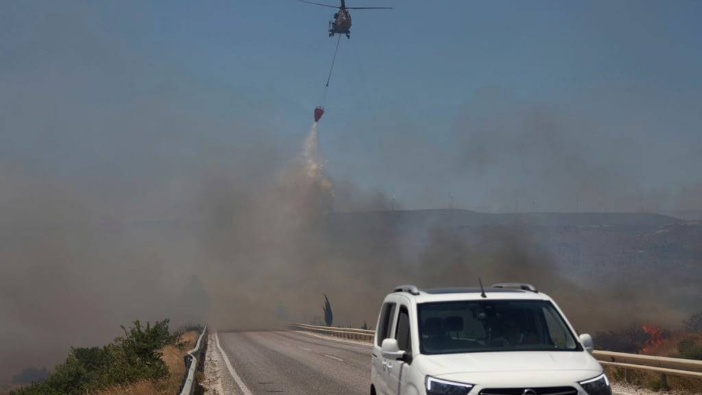 ARCHIV - Ein Hubschrauber wirft Anfang Juli Wasser ab, um ein Feuer in Cesme, in der Nähe von Izmir zu bekämpfen. Foto: Cengiz Malgir/DIA Photo/dpa